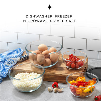 Three transparent glass bowls with lids sit on a wooden cutting board. The bowls are filled with colorful vegetables and eggs.