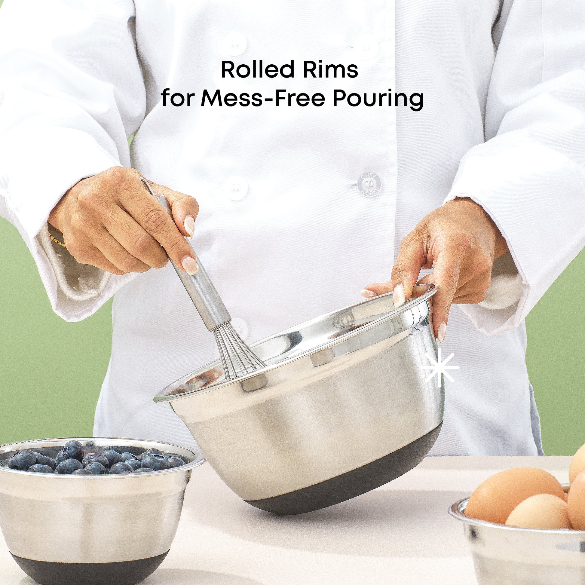 Chef holding a mixing bowl with a whisk inside, smaller bowl with blueberries nearby and another bowl full of eggs, with text "rolled rims for mess free pouring."