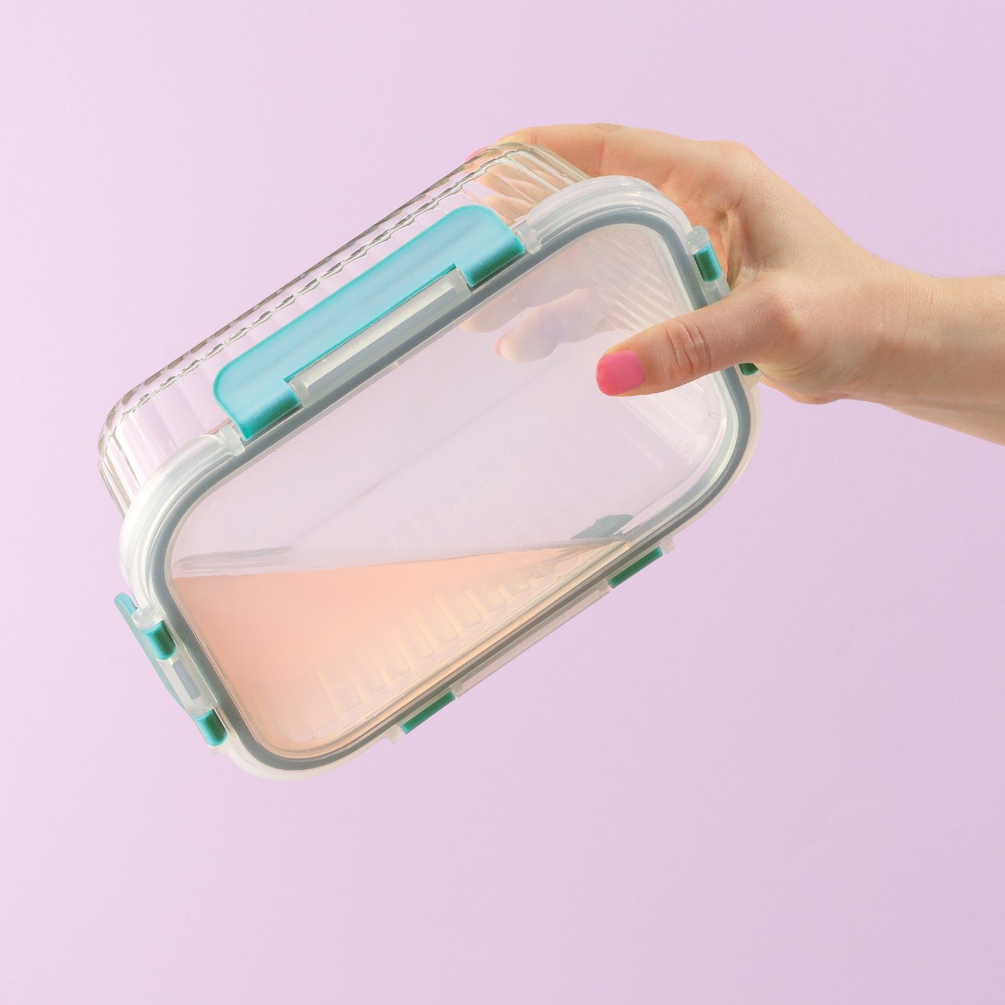 Hands holding a closed container with liquid inside, upside down, to demonstrate its leakproof feature.