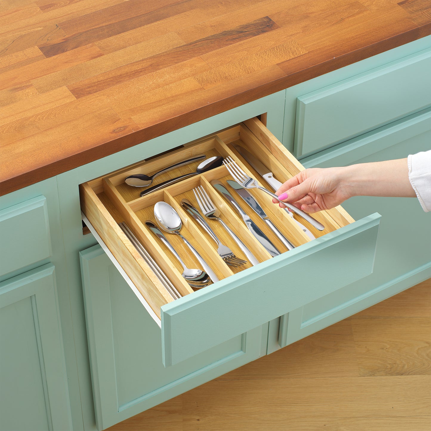 Hand putting away silverware into an open drawer with the organizer neatly inside