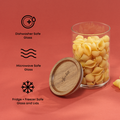 Glass container with wooden lid filled with pasta on a red background with safety icons and text" dishwasher and microwave safe glass, fridge and freezer safe glass and lids"
