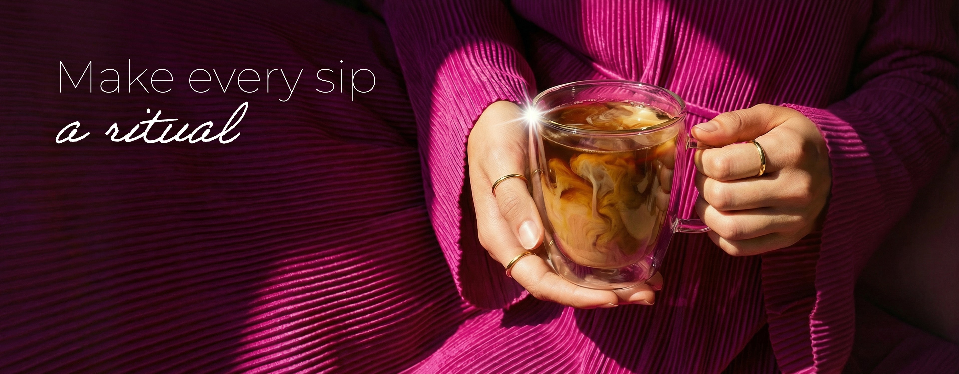 Person holding a double wall mug of coffee with a dark pink background and text 'Make every sip a ritual'.