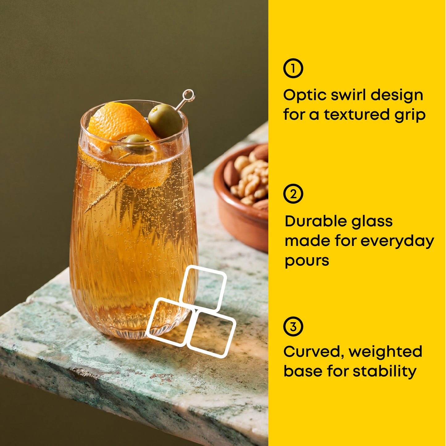 Glass of orange juice with garnishes on a stone surface, accompanied by text about glass features.