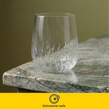 A clear cut-crystal glass with a textured wavy pattern, shown on a green marble surface with a yellow banner at the bottom reading 'Dishwasher safe'.